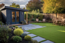 View Of A Back Garden With Artificial Grass, Grey Paving Slab Patio, Summer House Garden Timber Outbuilding, Fish Pond