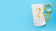 © MohamadFaizal - Questions and answers concept. Qna and faq. Question symbol written on a paper. Blue background with copy space.