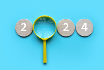 Fototapete - New year concept. Magnifying glass with a wooden circle with number over a blue background.	