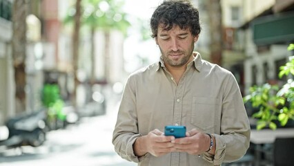 Poster - Young hispanic man smiling confident using smartphone at street