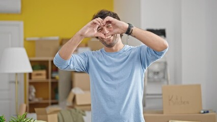 Wall Mural - Young hispanic man doing heart gesture at new home