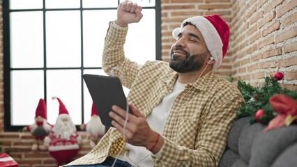 Sticker - Young hispanic man using touchpad celebrating christmas at home