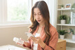 © KMPZZZ - Health care asian young woman using smart phone for reading, searching prescription on bottle medicine, pill label text about information online, instructions side effects, pharmacy medicament concept