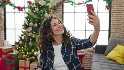 Canvas Print - Middle age hispanic woman taking a selfie picture celebrating christmas at home