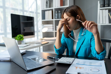 Wall Mural - Stressed, tired, sleepy businesswoman bored from sitting at a desk for long hours and having office syndrome while working with laptop and financial paperwork. office marketing.