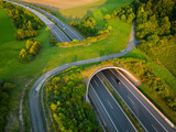Fototapeta Miasta - Aerial view of a green overpass over almost empty highway.