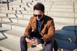 © baranq - Businessman sitting on stairs in the city using mobile phone
