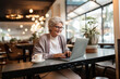 © uv_group - Portrait of senior woman with grey hair working on laptop in cafe