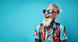 © mozZz - A happy and cool senior hipster with a big smile, relax, positive attitude, laughing on an empty blue background. Active lifestyle concept for seniors: Sunset of life in colors