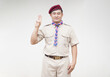 Handsome Asian man wear boy scout uniform, red cap, blue and pink striped scarf, make hand sign symbol of scout. Concept, educational career with uniform in school, Thailand.  