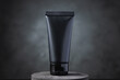 Black cosmetic squeeze tube on black circular podium.