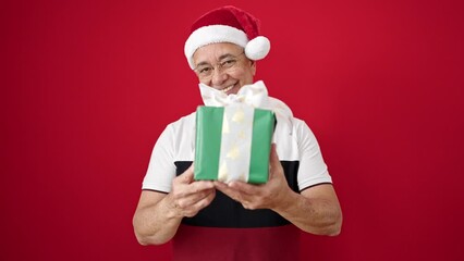 Poster - Middle age man with grey hair smiling confident wearing christmas hat over isolated red background