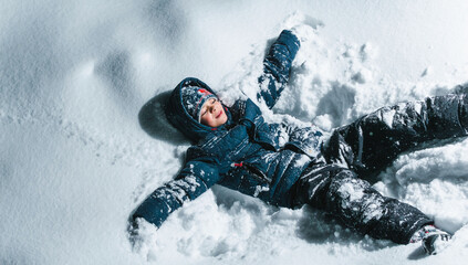 A little boy is playing in the snow in the evening