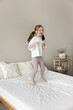 © fizkes - Happy adorable toddler girl singing song at brush microphone, dancing to music on bed, having fun, playing singer celebrity, enjoying funny activity, motion, leisure at home