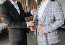 A Friend Of The Groom Helps The Groom In A Stylish Gray Suit In Preparation For The Wedding In The Morning With Clothes. Close-up Photography, Portrait.