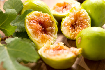 Poster - Fig fruits macro shot. Ripe sweet yellow and green figs fruit with leaves on wooden table close up, vegan food background 