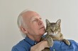 Portrait of an elderly happy gray-haired man with a pet cat in his arms