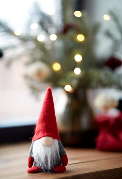 holidays, decoration and celebration concept - close up of christmas gnome and fir branches in vase on window sill at home