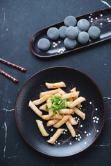 Wall Mural - Korean tteokbokki or rice cakes and mochi on a black marble background, vertical shot, top view