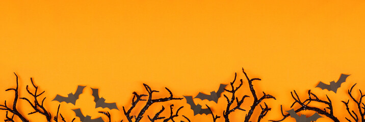 Wall Mural - Halloween bottom border of spooky bats and black branches. Top view over an orange banner background with copy space.