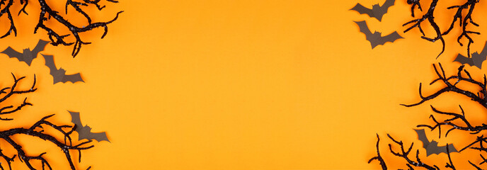 Poster - Halloween double border of spooky bats and black branches. Above view over an orange banner background with copy space.