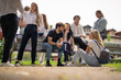 © qunica.com - College students studying together, discussing subject before exam sitting in the park.