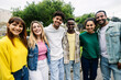 Young group of happy multiracial student friends looking at camera standing together outdoor. Smiling millennial people hugging each other posing for photo.
