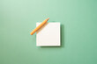 White memo paper, sticky note pad with colored pencil on green background. top view, copy space