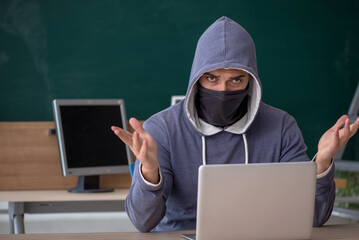 Wall Mural - Young male hacker sitting in the classroom