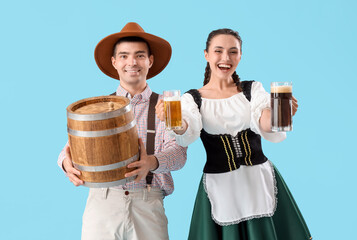 Young couple in traditional German clothes with beer on blue background