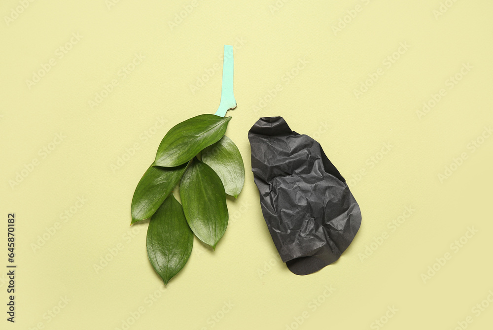 Diseased paper lungs with leaves on green background. Lung cancer concept