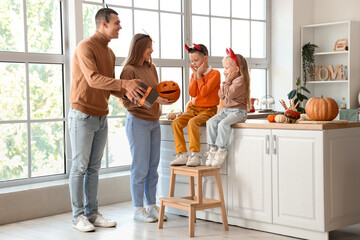 Poster - Happy parents greeting their little children with Halloween gift in kitchen