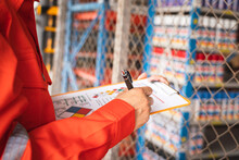 A Worker Is Checking On The Hazardous Chemical Material Information Form With Background Of Chemical Storage Area At The Factory Place. Industrial Safety Working Action. Selective Focus.	
