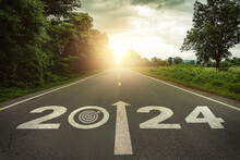 Goals, Targets In New Year 2024 Or Straightforward Concept. Text 2024 And Dartboard With Dart Icon On The Road In The Middle Of Asphalt Road At Sunset. Life, Business Planning, Challenge, Strategies.