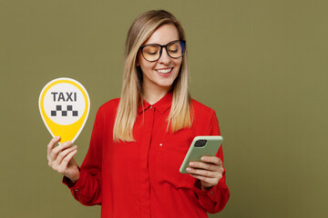 Wall Mural - Young fun woman she wears red shirt casual clothes glasses hold in ahnd taxi card sign use mobile cell phone booking cab isolated on plain pastel green background studio portrait. Lifestyle concept.