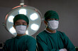 Two professional surgeon doctor standing under bright light, using surgical equipment to do surgery at hospital operating room. Surgical team operating surgery patient, healthcare and medical.