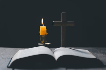 Canvas Print - Light candle with holy bible and cross or crucifix on old wooden background in church.Candlelight and open book on vintage wood table christianity study and reading in home.Concept of christ religion