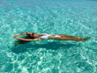 © Alona - A smiling girl in sunglasses, adorned in white swimwear, floats gracefully on her back, embraced by the crystal-clear ocean in the Maldives