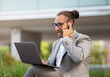 © Prostock-studio - Handsome millennial businessman making video call on laptop while sitting outdoors