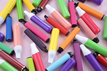 Wall Mural - Set of multicolor disposable electronic cigarettes on a pink background.