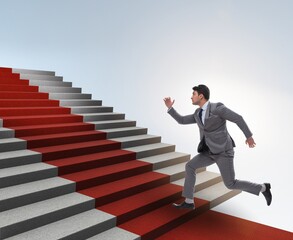 Wall Mural - Young businessman climbing stairs and red carpet