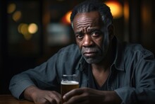 Middleaged African American Man, At City Pub, Nursing Drink With Contemplative Look. Expressions Reflect Struggle With Loss Of Dreams And Ambitions Due To Midlife Crisis. Denial Of This Reality