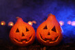 Two pumpkins with blue light and smoke