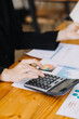 © ARMMY PICCA - Asian Businesswoman Using laptop computer and working at office with calculator document on desk, doing planning analyzing the financial report, business plan investment, finance analysis concept.