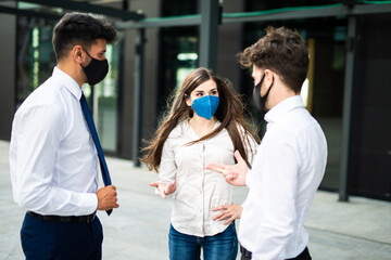 Wall Mural - Business partners discussing together outdoor wearing a protective mask against covid 19 coronavirus pandemic