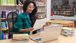 © SistersStock - Beautiful smiling curly-haired girl library employee, teacher or student, wearing glasses, sits at the study table sorting through papers getting ready for the start of the school year in the library.