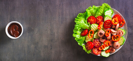  Salad of fried sausages, tomatoes, cucumber and lettuce on a plate top view web banner