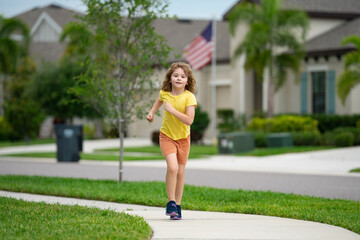 Canvas Print - Kid running in summer street. Child enjoy run. Little boy running on neighborhood street. Kids run on american city running road. Child boy running in park. Sports and fitness, run exercise for kids.