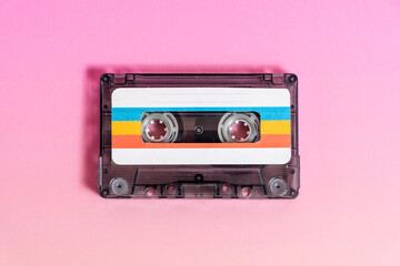 Transparent audio cassette with labels on fuchsia background.