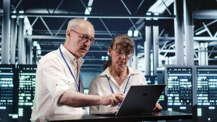 Poster - senescent colleagues looking around high tech data center, using laptop to crosscheck disaster recov
